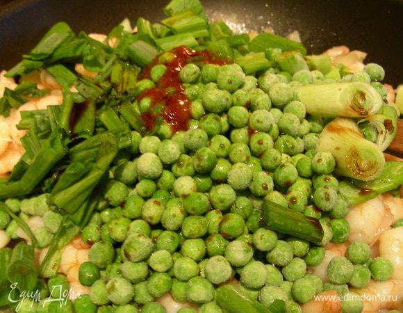 Зеленый лук тонко шинкуем. Добавляем его в сковороду, а также соус чили, соевый соус и зеленый горошек. Готовим, помешивая, минуты 3. 
