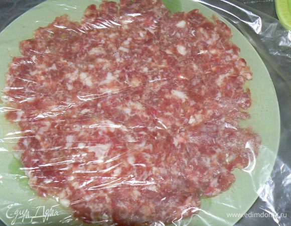 Снимите верхний слой целлофана с фарша и отправьте заготовку в яйцо фаршем вниз. Затем снимите второй слой целлофана.