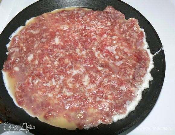 На раскаленную сковороду аккуратно выложите фарш с яйцом. Обжарьте с одной стороны.