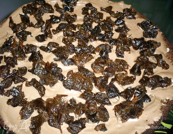 Начинаем сборку торта. Первый корж смазываем кремом и посыпаем нарезаным черносливом, и снова смазываем тонким слоем крема, чтобы спрятать чернослив. Так же поступаем со вторым коржом.