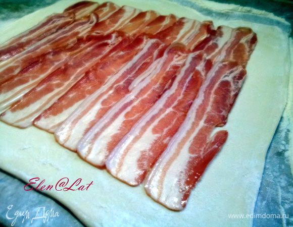Предварительно размороженное слоеное тесто, раскатать в пласт 45Х35см. Разложить полоски бекона.