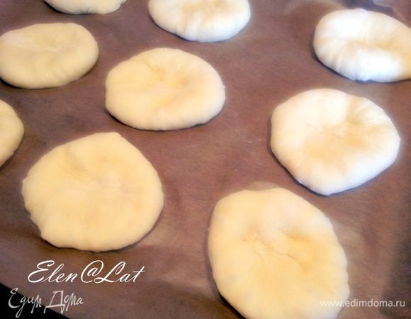 Шарики выложить на застеленный пергаментом противень на достаточно большом расстоянии. При выпечки булочки очень увеличиваются.
Когда шарики будут разложены, надо каждый шарик приплюснуть ладонью, чтобы получилась лепешка, не бойтесь нажимайте посильней. Дать расстояться.