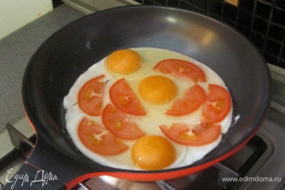 На разогретую сковороду вбить три яйца, помидоры нарезать тонкими ломтиками ,выложить сверху.