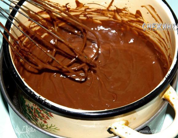 Теперь вводим в крем растопленный шоколад, размешиваем до однородности и снимаем с огня. Добавляем масло комнатной температуры. Вымешиваем крем и охлаждаем на водяной бане, всё время помешивая, чтобы на поверхности не образовывалась плёночка. Готовый крем ставим в холодильник.
