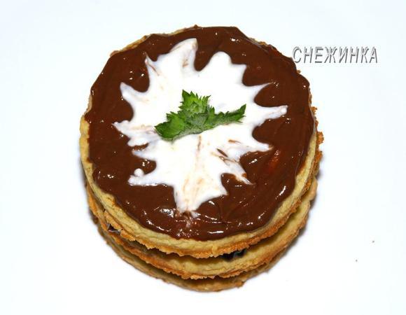 Теперь украшаем. Хорошенько растираем все ингредиенты для белого крема. Сверху в центр пирожного наливаем ложечку белого крема. С помощью зубочистки выполняем рисунок. Вставляем маленькую веточку мяты. 