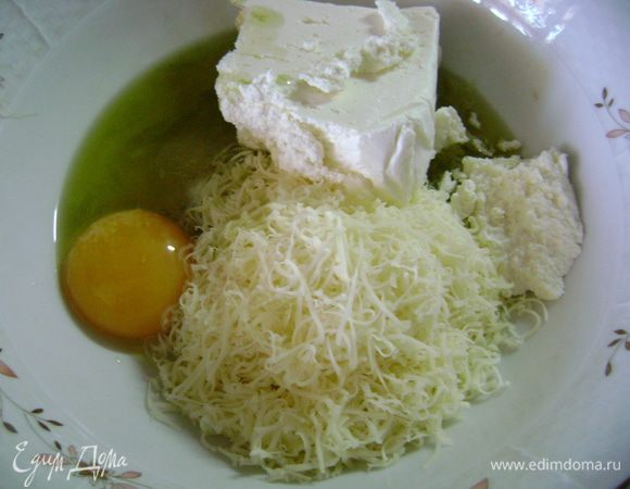 В глубокую чашку натереть сыр на мелкой терке, добавить творог, желток, соль, сахар и оливковое масло, перемешать.