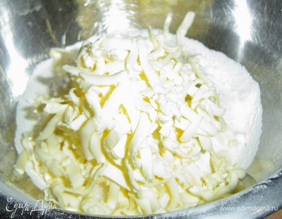 Высыпаем в миску 2/3 объема муки, соль, 50 г  сахара и натираем на терке охлажденное сливочное масло.