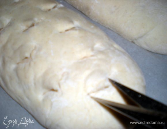 Слегка подпылить поверхность и выложить на неё тесто.Нужно отделить двухкилограммовый кусок и разделить его на 10 частей.Сформируйте багеты и накройте их полотенцем.Из оставшегося теста слепите 1 большой или 2 маленьких батона,также накройте полотенцем и оставьте на 1ч30м.Рисунок на батонах нужно делать острым ножом или ножницами.