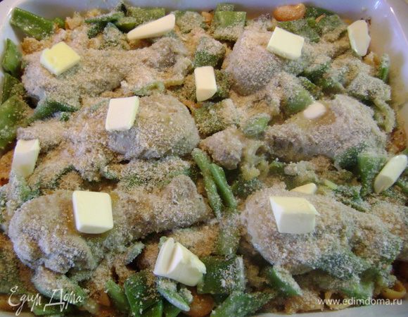 Уложить куриную смесь поверх слоя лапши, обсыпать толчеными сухарями и разложить сверху сливочное масло, нарезанное мелкими кубиками. 