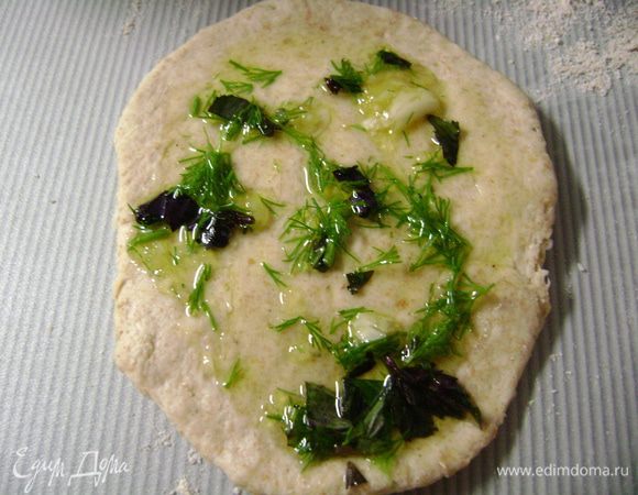 Тесто разделить на маленькие кусочки, раскатать на посыпанной мукой рабочей поверхности, смазать оливковым маслом с зеленью и закрутить рулетиком. 