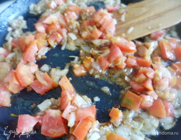 Нарезать помидор на небольшие кусочки, добавить к луку, продолжая обжаривать. Добавить измельченный чеснок и перемешать