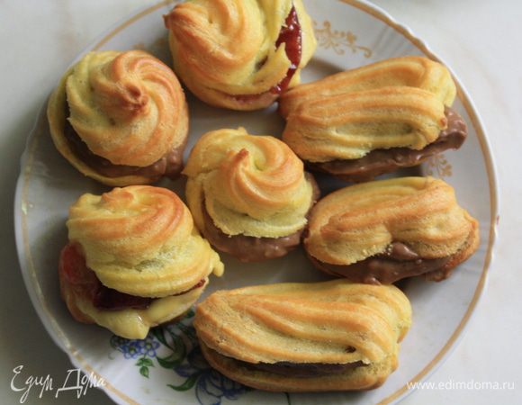 Ставим  духовку разогреваться. На противень кладем пергаментную бумагу. Ложкой или шприцом выкладываем темто на пергамент. Если используете ложку, то ее лучше смачивать в воде, так заварное тесто не прилипает. Выпекаем 20-25 минут при температуре примерно 180 градусов , потом снижаем до 160 и печем еще минут 10-15. ДУХОВКУ НЕ ОТКРЫВАТЬ, а то эклеры могут опасть. Вообще тут, конечно, очень важны индивидуальные особенности духовки, так как если эклерам будет жарко они могут подгореть, а холодно - не поднимутся, но тут хозяйке виднее))))