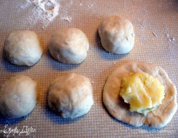 Делим тесто на две неравные части. 1/3 для пирожков и 2/3 для пирога.  Меньшую часть теста  разделим на 6 небольших шарика, из которых сформируем руками лепёшки для пирожков. В середину лепёшки положим по 1 ст. л. картофельного пюре.