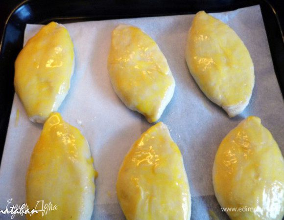 Лепим пирожки и выкладываем их "швом" вниз на противень (у меня противень маленький 29х30 см) , застеленный пергаментом. Смазываем  пирожки взбитым яичным желтком.