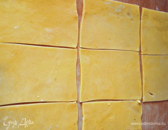Тесто тонко раскатать на слегка присыпанной мукой поверхности. Нарезать прямоугольниками размером примерно 12*8 см. 