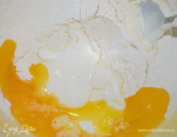 Добавьте просеянную с разрыхлителем муку и сметану.