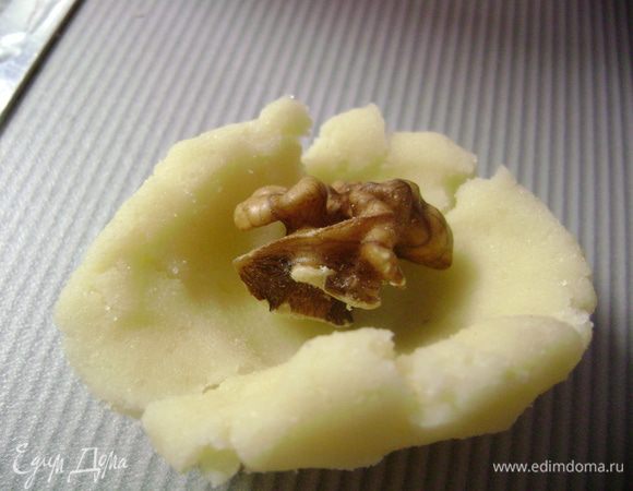 От теста отщипить небольшой кусочек, сформировать лепешку, а внутрь положить грецкий орех. 