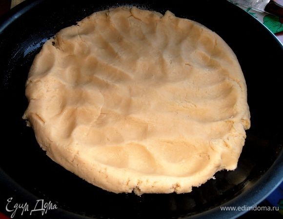 Достаём из холодильника тесто и начинаем раминать его руками по смазанной маслом широкой форме.
