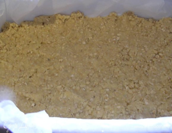 Форму с низкими стенками смазываем маслом и выкладываем в нее половину теста. Я использую бумагу для выпечки, так пирог потом легче достать. Тесто слегка утрамбовываем пальцами.