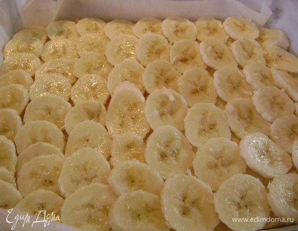 Вынуть форму с тестом из духовки, разложить по поверхности кружки бананов.