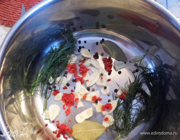 На дно кастрюли выложить половину зелени, чеснок, острый перец, лавровый лист, смесь перцев-горошков.