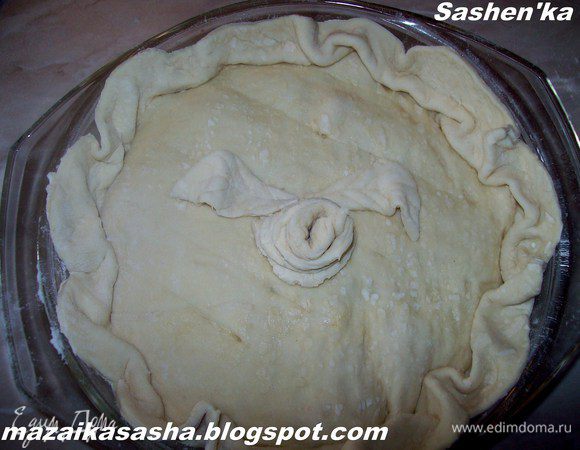 1 лист слоеного теста раскатать и вырезать его по форме запекания + 3 см. (тесто как Вы поняли должно быть больше формы) Выкладываем его поверх начинки, по краям формы формируем складки. Плотно не прижимаем, что бы в процессе выпекания выходил пар. Острым ножем делаем легкие надрезы, но не прорезая тесто на сквозь. Из оставшихся обрезков делаем розочку и пару листиков.