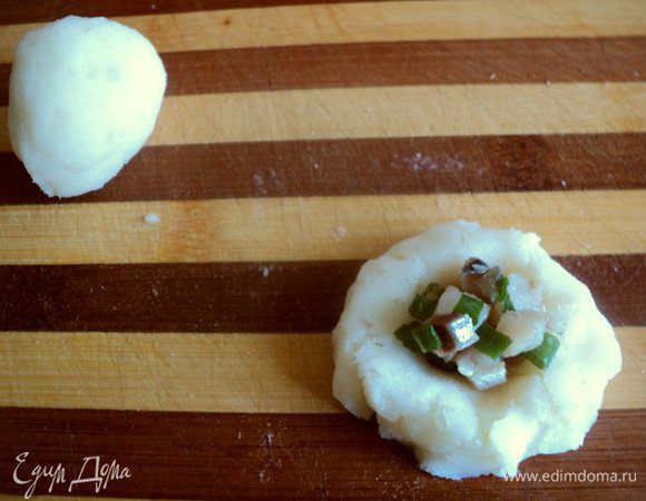 Взять 1 ст. ложку картофельного пюре, скатать шарик, затем приплюснуть и сделать углубление в центре. Положить в центр 1 ст. ложку начинки из сельди, защипнуть края и сформировать «клубничку».