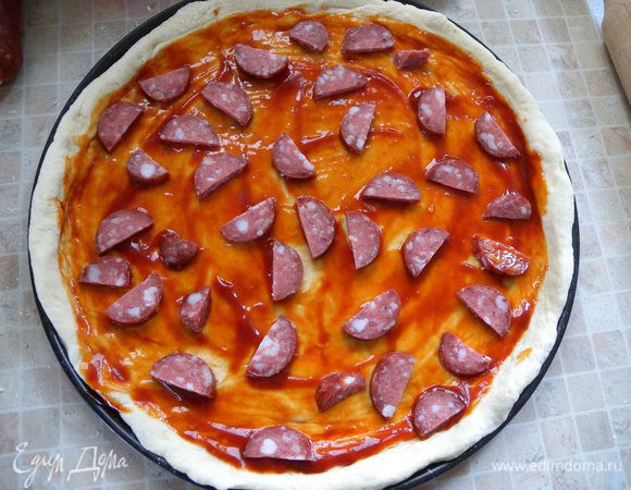 Порезать колбаски на кусочки и на тесто. 