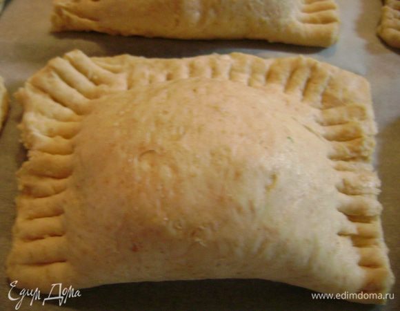 Уложить пирожки на противень, застеленный пергаментной бумагой, и вилкой прижать края.