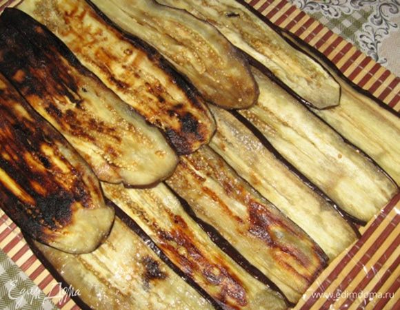 Теперь формируем рулет. Возьмите пищевую пленку, сложите ее вдвое "по толщине" и внахлест в ширину, длину регулируйте сами с таким расчетом, что вам рулет в нее хотя бы на пару оборотов завернуть нужно будет. Теперь внахлест краями выложите баклажаны по ширине не больше 6-ти кусков и в длину не больше 2-х. Хорошо посолите и поперчите.