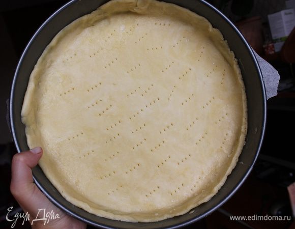 Достать охлажденное тесто из холодильника и слегка месить руками, пока оно не станет эластичным. Затем раскатайте скалкой в разных направлениях. Сформировать круг или квадрат (в зависимости от формы). Накрутите тесто на скалку и переместите в форму, смазанную сливочным маслом. Хорошо по всей поверхности наколите тесто вилкой.  