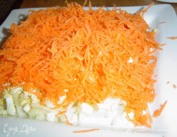Морковь очищаем, натираем на мелкой терке и выкладываем на яичный слой, смазываем соусом - это четвертый слой.