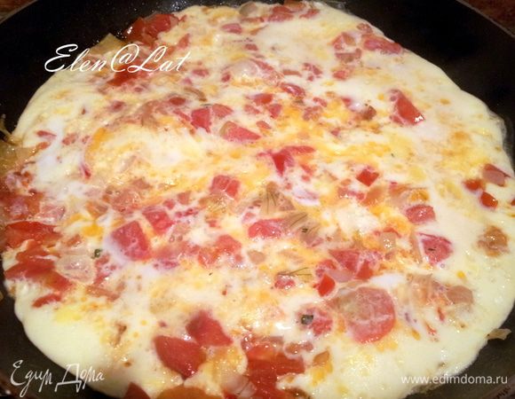 Для омлета взбить яйца и залить ими обжаренный лук и помидоры, прикрыть сковородку крышкой и довести до готовности.