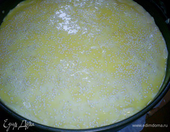 Оставшуюся часть теста раскатываем на бумаге или силиконовом коврике, переносим на пирог и аккуратно отделяем бумагу (коврик) от теста. Яйцо взбиваем с маслом, смазываем верх пирога и посыпаем кунжутом.