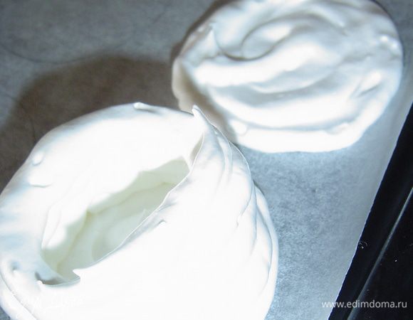 Противень застилаем пергаментной бумагой, слегка смазанной маслом. Взбитые белки помещаем в кулинарный мешок(а можно просто выложить ложкой, а затем сделать в центре углубление) и отсаживаем округлое дно,а по окружности бортики.