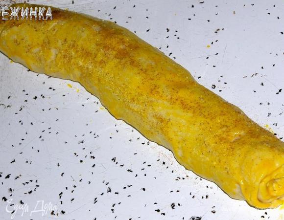 Духовку разогрейте до 190°C. Рулет переложите на противень. Смажьте желтком и присыпьте сахаром и корицей (0,5 ч. л.).