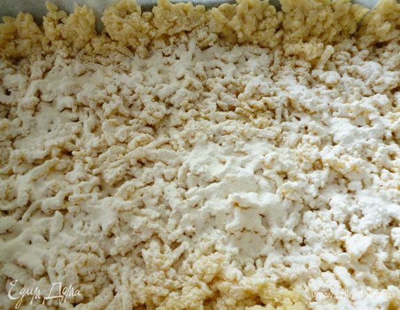 Форму для выпечки выстелить пергаментом, смазать маргарином и присыпать манкой. Берем по одной части теста из холодильника и трем его через терку на противень. Аккуратно распределяем и формуем бортик. Затем через сито распылить крахмал, чтобы тесто не намокало от ягод и начинки.