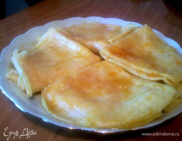 Быстро окунуть в масло поочерёдно все блинчики, сложить пополам, красивой стороной наружу, и ещё пополам, клинышком. 
Красиво уложить блинчики на тарелку, полить оставшимся апельсиновым маслом.
