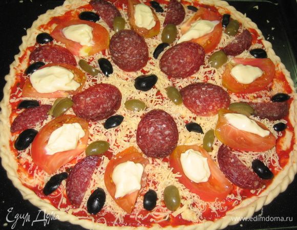 Разложить по поверхности порезанный помидор, колбасу и оливки. На каждый ломтик помидора уложить чайной ложкой плавленный сыр