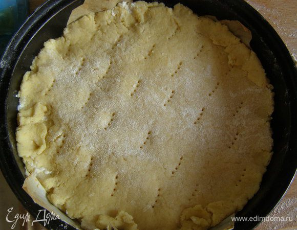 Меньшую часть раскатать по диаметру формы, залепить края, наколоть вилкой.