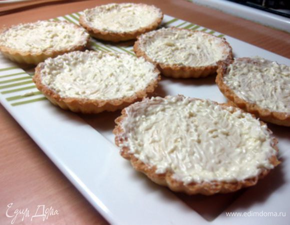 Выпекать тарталетки 20-25 минут в разогретой до 200оС духовке.
Готовые тарталетки остудить, затем достать из формочек и выложить на блюдо.
Белый шоколад растопить на водяной бане и нанести та тарталетки тонким слоем.
Убрать тарталетки в холодильник, чтобы шоколад застыл.