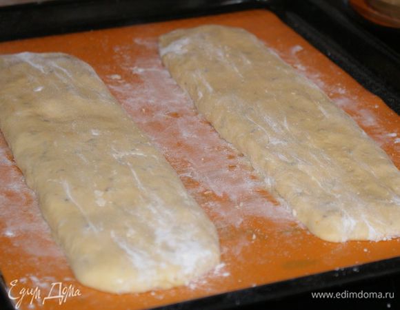 Застелить противень бумагой для выпечки или сбрызнуть маслом. Я использовала силиконовый коврик, его ничем не смазывала. Разделить тесто на 2 части и выложить его на противень. Немного посыпать мукой сверху и сформировать руками 2 полоски длинной 25–30 см и шириной 5–7 см.