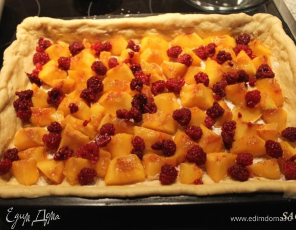 Большую часть немного раскатаем по размерам формы, выкладываем (у меня размеры 20 на 30 см) так, чтобы немного свисали края с бортиков. Выкладываем порезанные крупными дольками персики. У меня было немного малины, я её раскидала живописно.:) Можно немного присыпать сахаром, если фрукты несладкие (бывает такое).