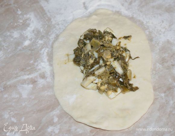 От теста отщипнуть небольшой кусочек и расскатать его не очень тонко на присыпанном мукой столе. Выложить в середину 1 ст. ложку начинки.