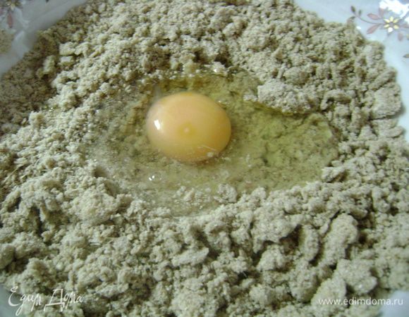 Собрать смесь горкой, сделать углубление и влить туда яйцо и 2 ч.л. воды. Перемешать, чтобы получилось плотное, но не сухое тесто, в случае необходимости добавляя оставшуюся воду.