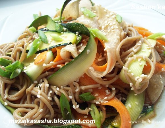 Готовую лапшу слить, перемешать с овощными лентами. Дабавить мелко нарезанный зеленый лук. Заправить соевым соусои и присыпать кунжутом.