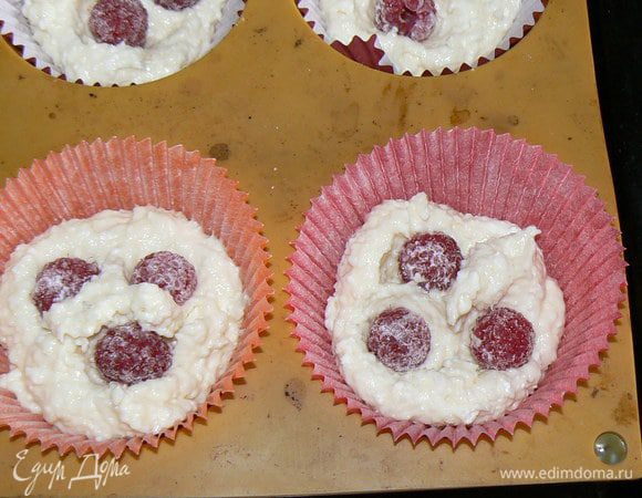 в бумажные формочки положить часть теста,вдавить ягоды малины
