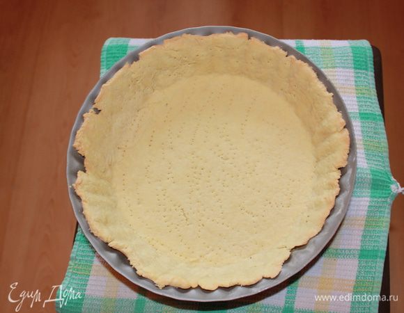 Тесто раскатайте скалкой на рабочей поверхности, уложите в форму, сформировав бортики. Излишки теста обрежьте. Тесто в нескольких местах наколите вилкой. Сверху уложите кулинарный груз (пергамент и бобы, возможно рис, горох)  Запекайте в разогретой до 200 гр. духовке 10 минут. Затем аккуратно снимите груз и держите в духовке еще 7 минут до золотистого цвета. 