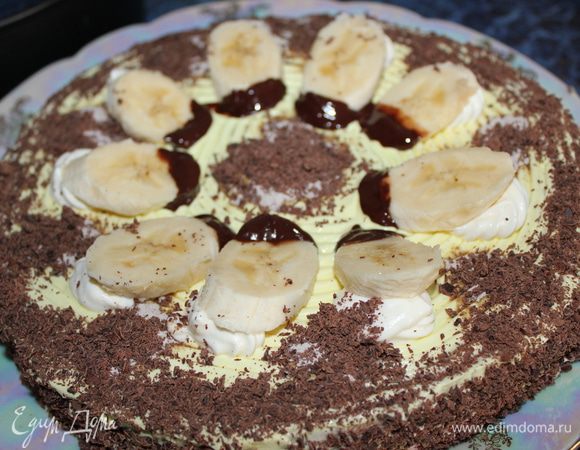 Банан очистить и разделить на 8 или 9 частей (как было у меня) наискось. Каждый кусочек смазать шоколадом на 1/2 и уложить на сливки, которыми мы предварительно из шприца украсили торт (8 или 9 разочек из сливок). Бока у торта украсили тертым шоколадом плюс можно посыпать и верх торта тоже (по вашему желанию).
