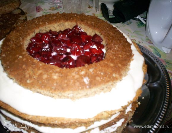 Всю поверхность смазываем кремом, дальше собираем в такой последовательности: коричневый корж, крем, белый корж, крем, оставшееся кольцо. Кольцо выкладываем посредине белого коржа и заполняем вишнями. Если планируете их залить желе, проследите, чтоб вишни НЕ заполнили кольцо до краев.